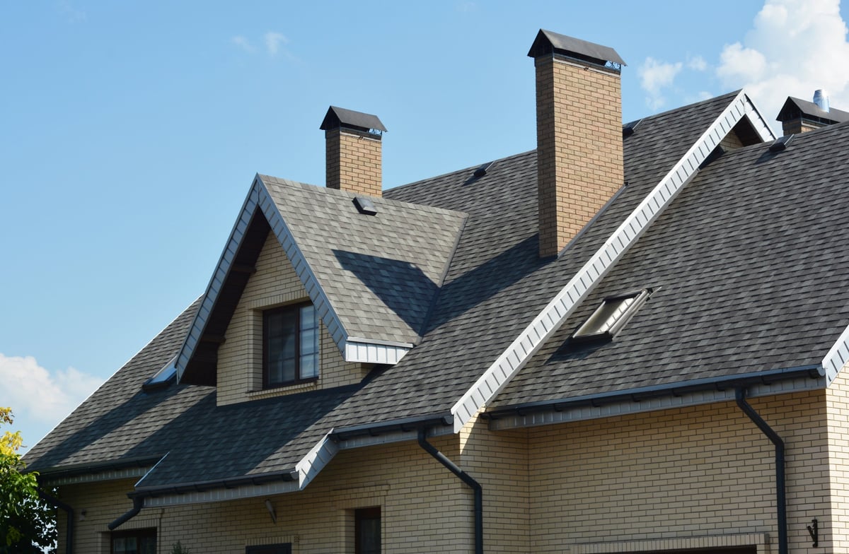 House asphalt shingles rooftop with dormer window and skylights