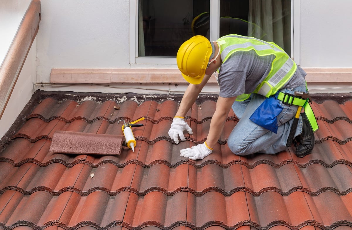 Construction worker inspecting cracked roof tile