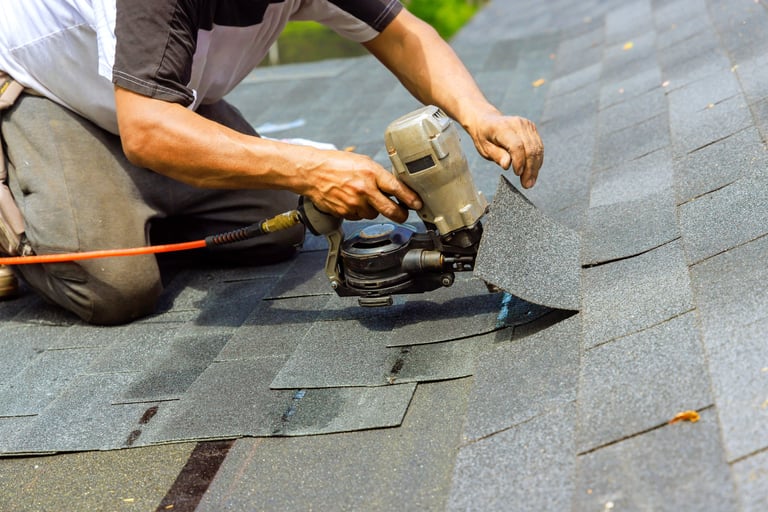 Roofer installing bitumen shingles with nail gun