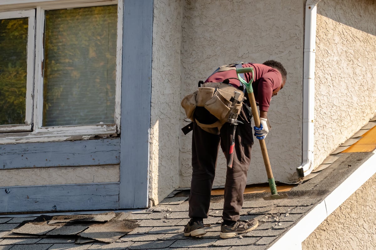 Roofer in work gear repairing damaged roof