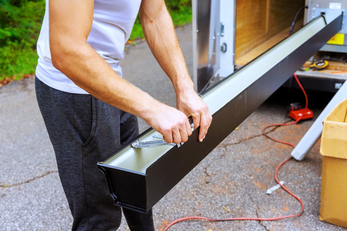 Man works on metal gutter channels with tool