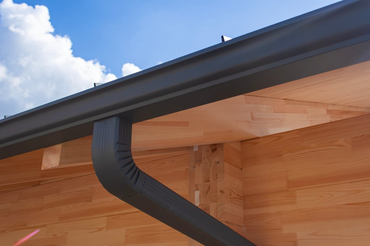 Close-up of contemporary dark gray rain gutter and downspout system
