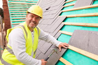 Construction worker laying slate tiles